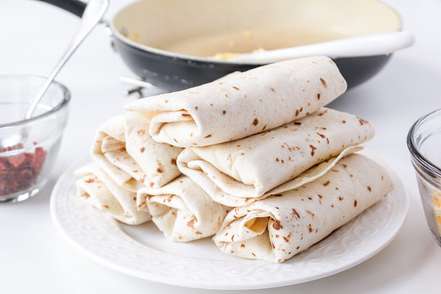 stack of rolled burritos on a white plate.