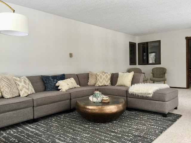 neutral grey, cream, and black living room with grey sectional sofa and arched lamp,