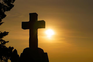 stone cross against sunset