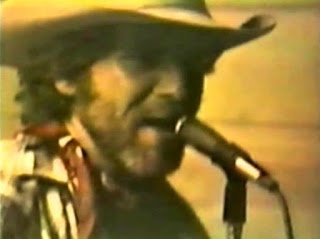 A bearded John Fogerty in a cowboy hat performing at Troy, Oregon