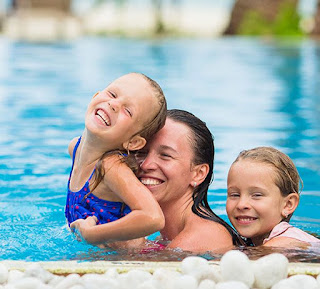 image of 2 children, a girl and a boy in an Indoor Pool in Toronto smiling, hugging and playing with an adult female