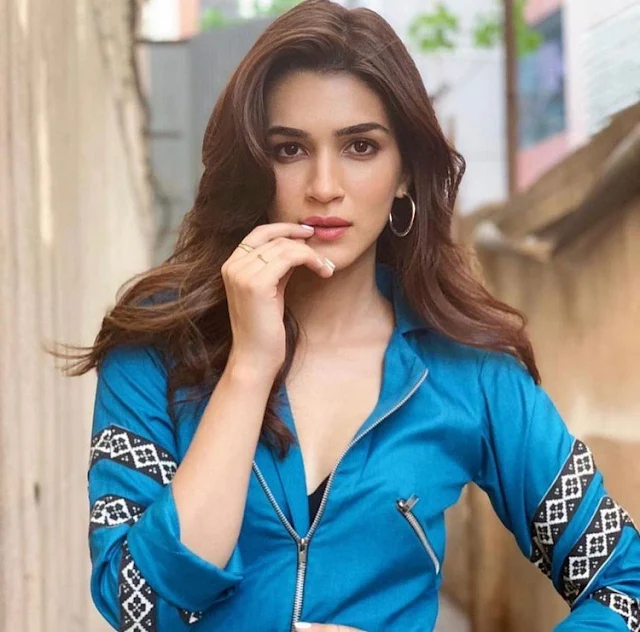 Bollywood actress Kriti Sanon in a blue shirt and grey pants, exuding confidence and style.