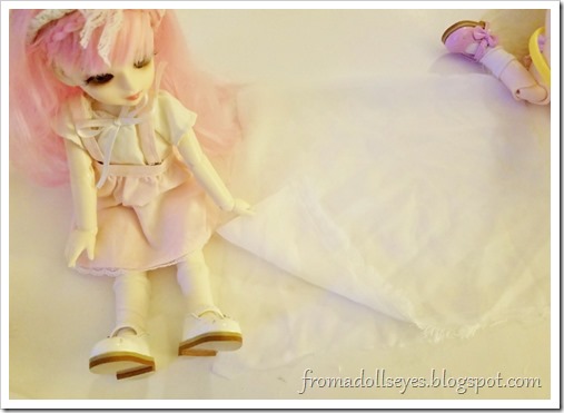 The pink haired bjd (Yuna) is folding a piece of fabric in half. The pink haired bjd (Yuna) is folding a piece of fabric in half.