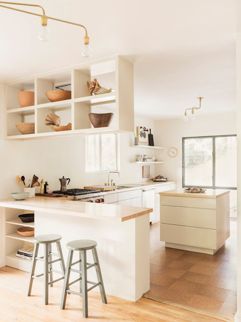 neutral kitchen with white cabinets, open shelving filled with collected antique bowls, and mint bar stools