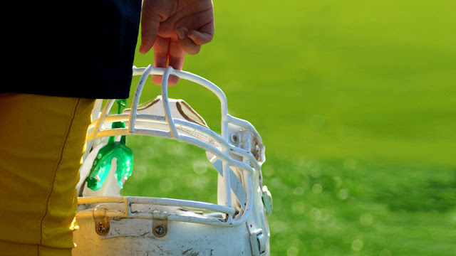 boy holding football and mouthguard