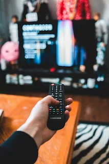 A male hand pointing the tv remote controls at the tv set; in control!