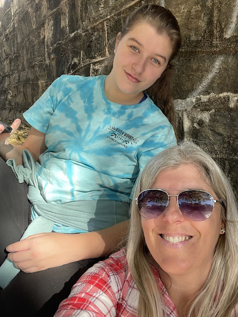 Me and Margie sitting with our backs to a rock wall beside that river/waterfall in Greensboro/Greenville? South Carolina.