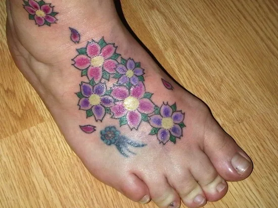 vemos a una mujer con los pies desnudos , lleva un tatuaje en el pie