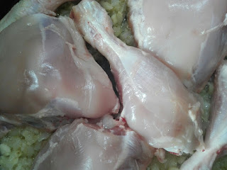 Imagen del pollo en la sartén con cebolla pochadas y ajos