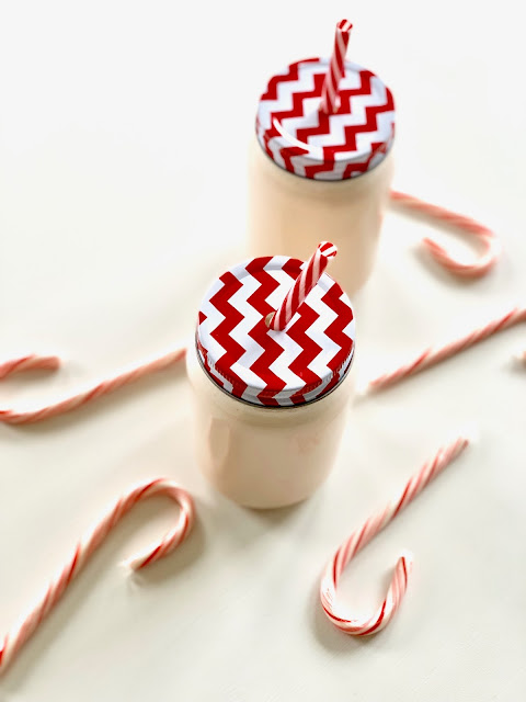 Pink milk punch in clear glass jars with red and white striped lids