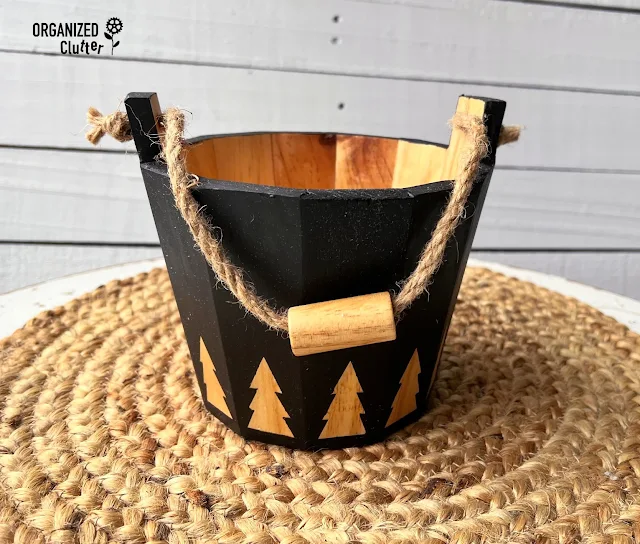 Photo of a thrifted wooden bucket with a Frog Tape traced tree stencil border.