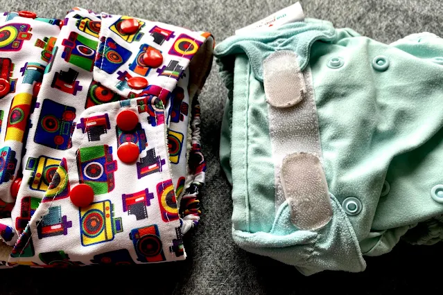 Two nappies side by side one with velcro one with poppers