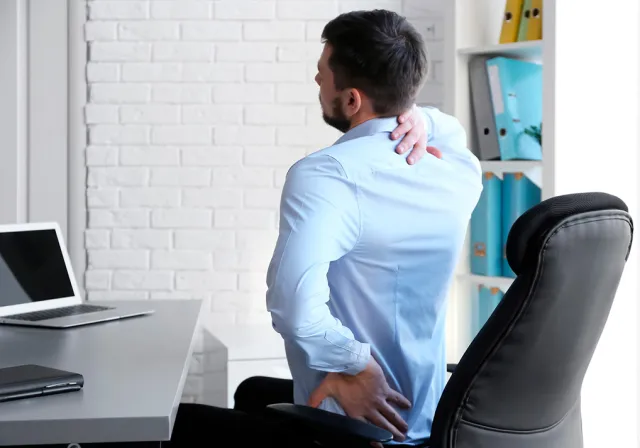 HOMEM COM DOR NAS COSTAS EM UMA CADEIRA DE ESCRITÓRIO