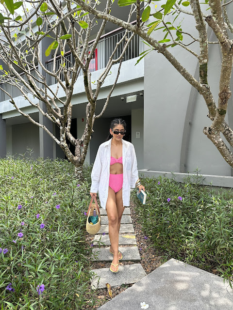 Outfit of a pink high waisted bikini with a white shirt cover up and a beach bag