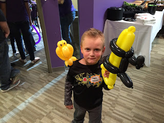 A young boy with a balloon parrot and a balloon gun