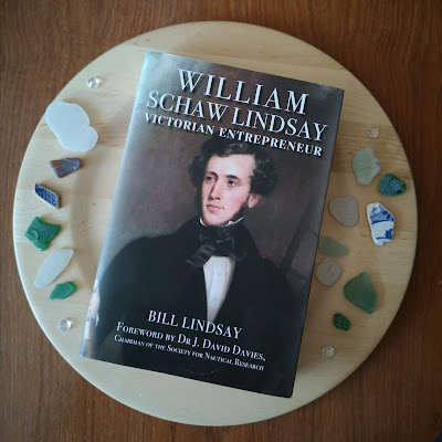 Front cover of William Schaw Lindsay by Bill Lindsay on wooden plate with sea glass and broken pottery