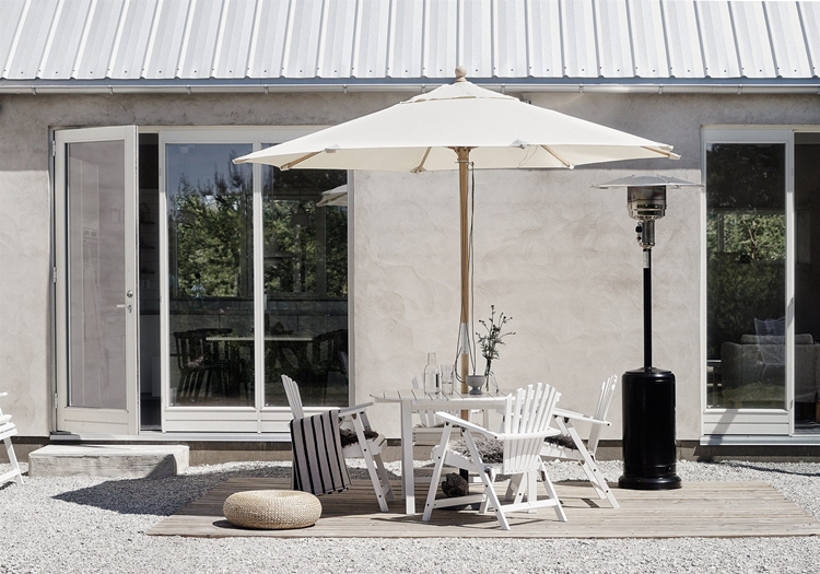 terraza-blanca-sombrilla-sillas-madera-conjunto-terraza-blanco-puerta-cristal-puff-estufa-decoracion-nordica
