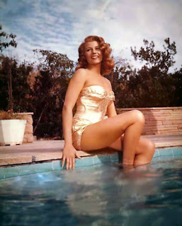 Rita Hayworth posed at edge of swimming pool wearing gold swimsuit from the 1950's