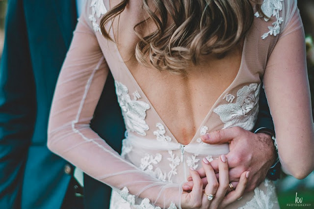 groom grabbing brides waist in lace wedding dress