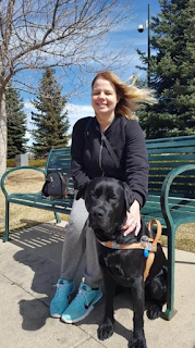 Maureen sitting on a bench with her guide dog