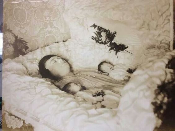 Fotografía post mortem de una madre con sus dos mellizos en el siglo XX.