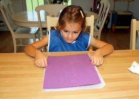 She lightly pressed a piece of construction paper onto the painted surface per the instructions.
