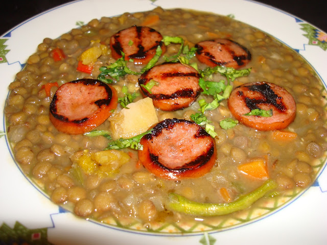PORTIONS: 6 1 PORCIÓN: 229 CALORÍAS INGREDIENTS 454 g (1 lb) lentejas. 560 cal. 114 g (4 oz) de Kielvasa. O use chorizos. Cortado en rodajas 375 cal. 2¼ litros (2¼ quarts) de caldo de pollo. O agua con dos cubitos bouillon de pollo. 100 cal. 1 cucharada de aceite. 120 cal. 1 taza de cebolla picada. 67 cal. 2 dientes de ajos picados. 8 cal. 1 taza de zanahoria cortada en cuadros. 52 cal. 1/3 taza de pimientos rojos cortados en cubitos. 13 cal. 1 taza de zapallo cortado en cubitos. 63 cal. 1/3 taza de pimientos verdes cortados en cuadros. 9 cal. 1/3 taza de apio cortado en cuadros. 4 cal. 1 cucharadita de sal o a su gusto. ¼ cucharadita de tomillo. ¼ cucharadita de orégano 1 hoja de laurel PREPARACIÓN Calentar una olla con el aceite y freír la cebolla con el ajo, sin dorar. Agregar zanahoria, pimientos rojos, zapallo y cocinar hasta que suelte color y olor. Añadir pimientos verdes, apio, tomillo, orégano, laurel y cocinar por un par de minutos. Verter el caldo de pollo (o agua con cubitos bouillon de pollo)y  lentejas. Tapar la olla  y cocinar a fuego moderado hasta que las lentejas estén blandas. Cocinar las rodajas de salchicha en una parrilla. Servir las lentejas con rodajas de salchicha s sobre las lentejas.