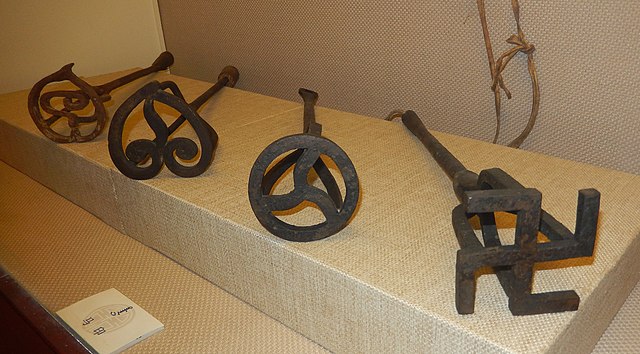 Four metal branding irons, including one with a swastika on the end.