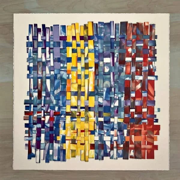 woven paper quilt composed of strips in shades of blue, yellow, and red