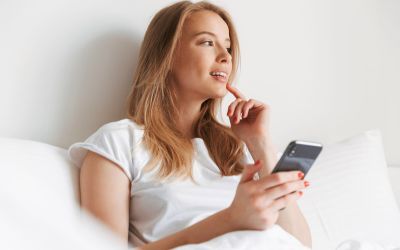 A cartoon of a young woman holding an Android phone in her hand and smiling while using ChatGPT to write a catchy blog title on a text editor app