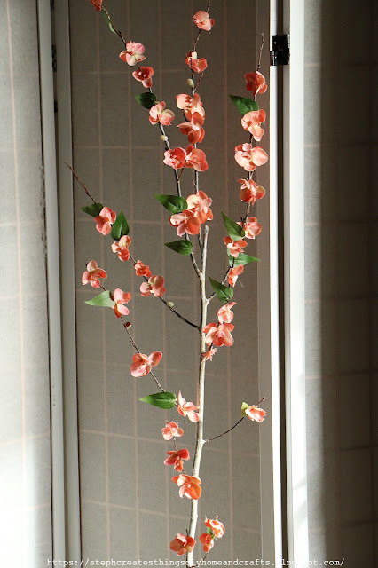 Tree branches with faux orange blossoms and green leaves