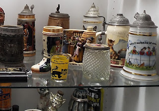 Several beer steins and other glassware, all with cats on them. American Museum of the House Cat.