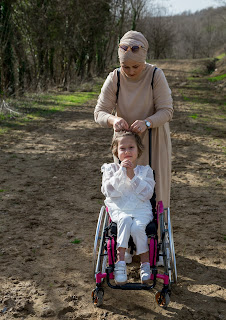Lady standing by a child in a wheelchair
