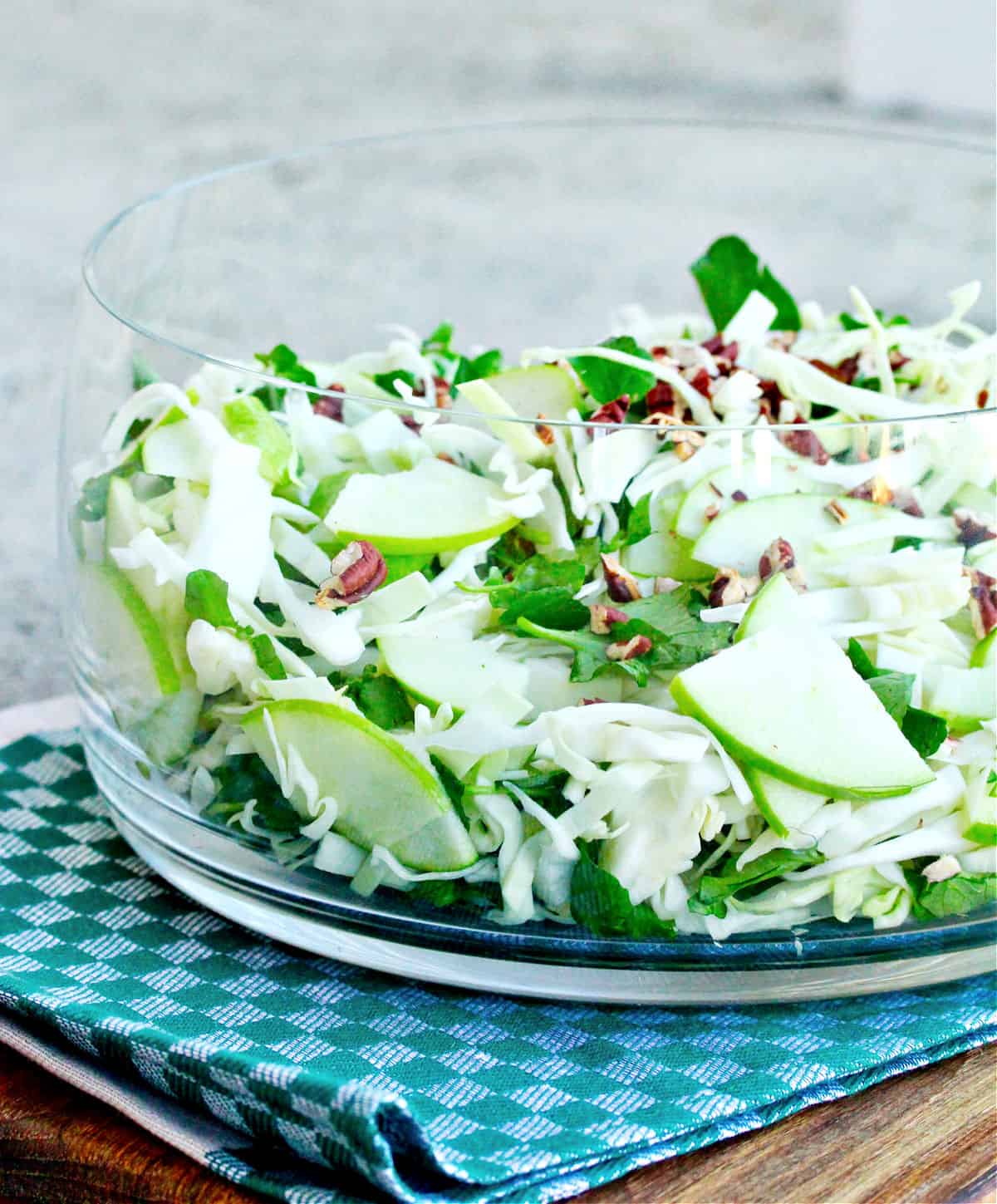 Green Cabbage and Apple Salad with Watercress and Pecans in a glass bowl.