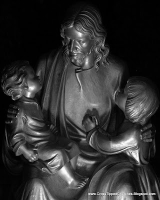 Night shot of statue of Jesus holding children.