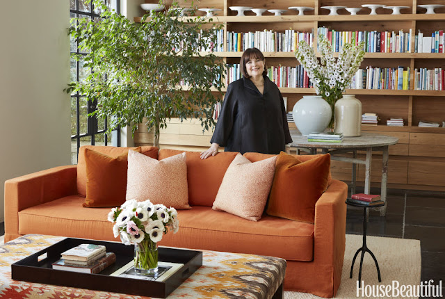 Ina Garten standing near bookshelves and orange sofa in East Hampton home