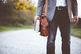 a man with a leather bag and a book in his hand