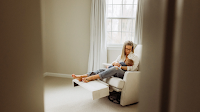 A mom seated on a recliner and breastfeeding her baby