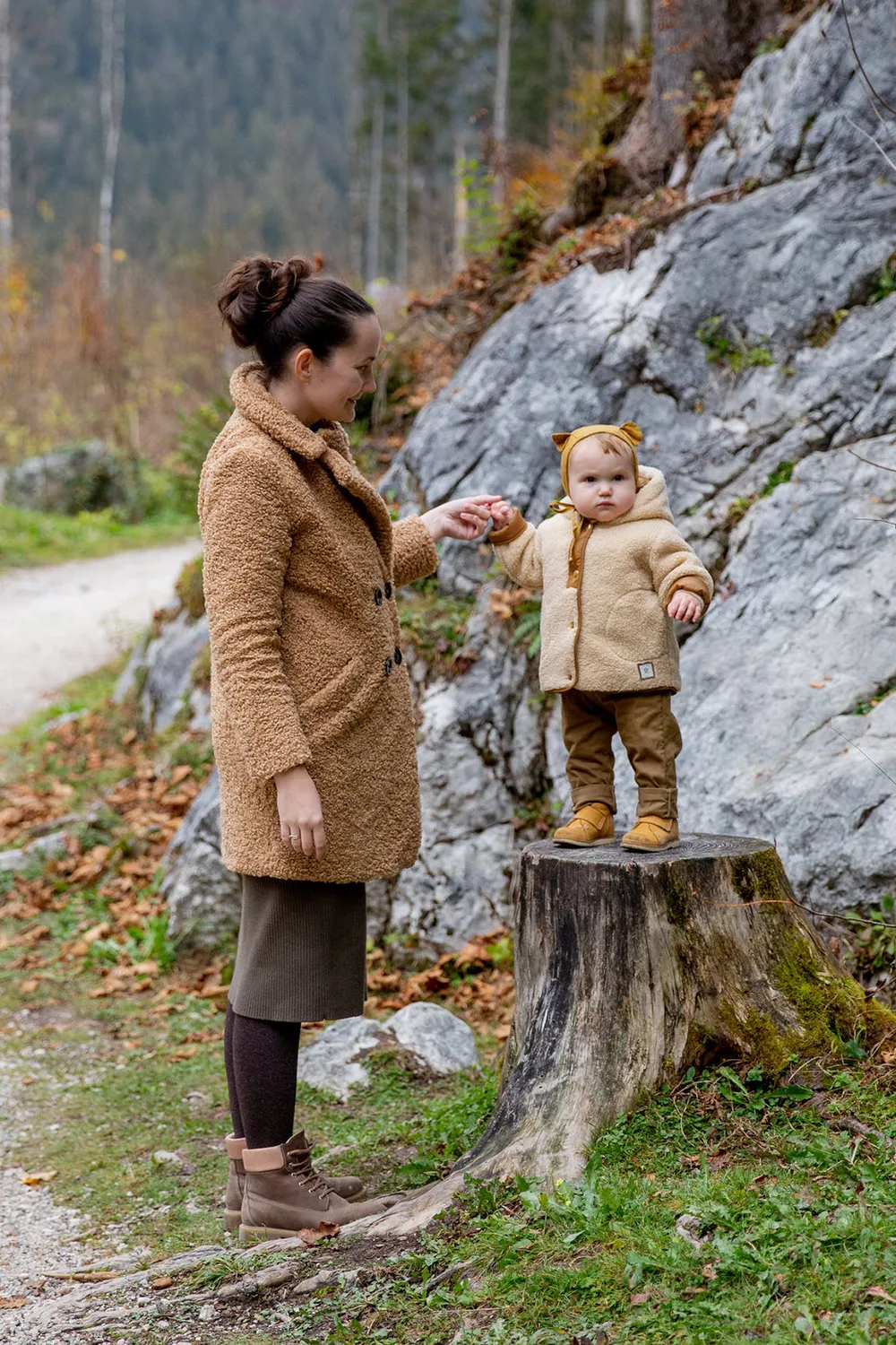 mom and her baby are wearing matching outfirts and pose in the forest