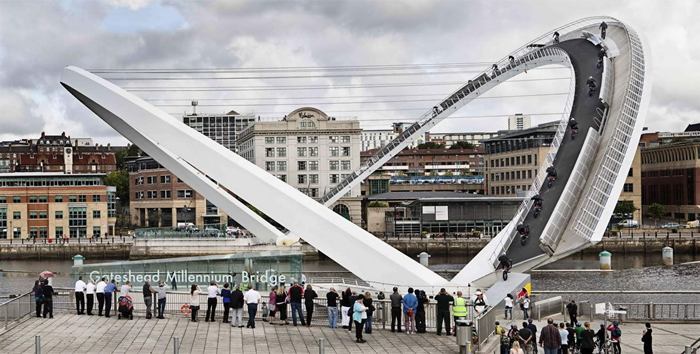 The Gateshead Millennium Bridge is a pedestrian and cyclist tilt bridge spanning the River Tyne in England between Gateshead's Quays arts quarter on the south bank, and the Quayside of Newcastle upon Tyne on the north bank. The award-winning structure was conceived and designed by architects Wilkinson Eyre and structural engineers Gifford. The bridge is sometimes referred to as the 'Blinking Eye Bridge' or the 'Winking Eye Bridge' due to its shape and its tilting method. In terms of height, the Gateshead Millennium Bridge is slightly shorter than the neighbouring Tyne Bridge, and stands as the sixteenth tallest structure in the city.