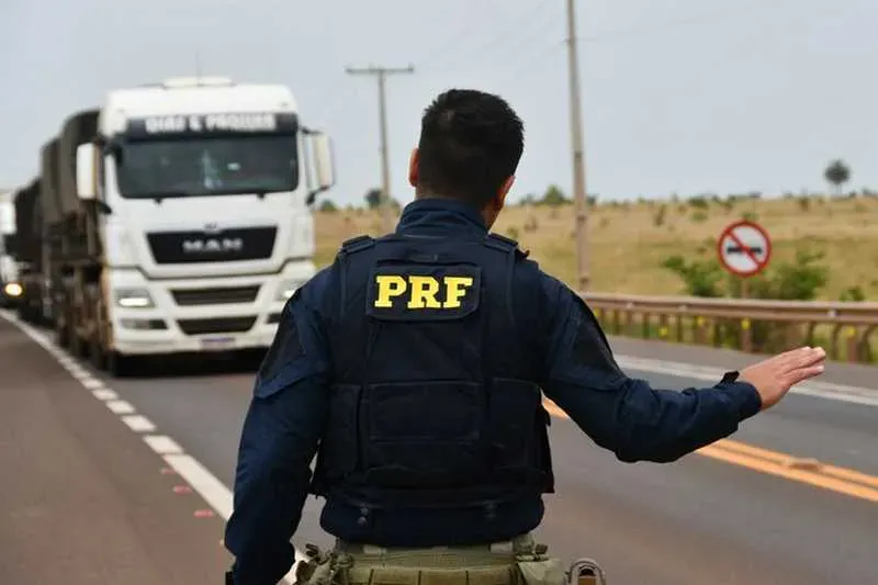 Agente da PRF abordando caminhão em rodovia federal de pista simples