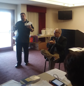 Rev Giovanni Arroyo reads a report, Rev. Leo Yates offers ASL interpretation