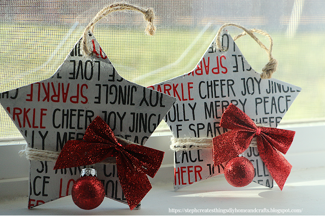 Two decoupage wooden stars with a red bow and mini red ornaments attached