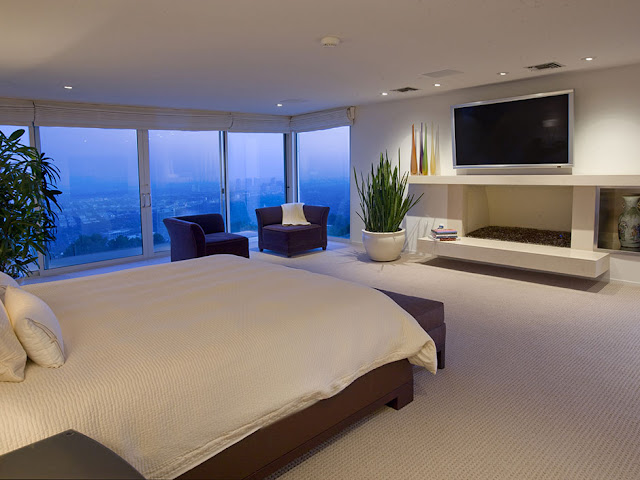 Picture of another large modern bedroom with large tv on the wall above the fireplace