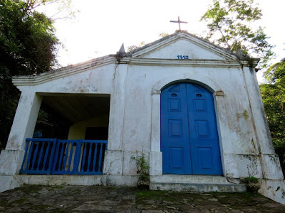 Frente da capela, edificação branca com detalhes em azul