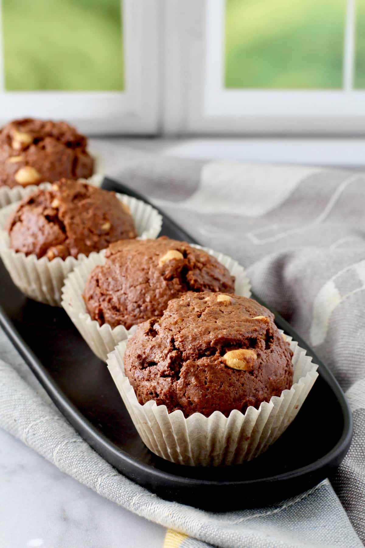 Chocolate Peanut Butter Chip Muffins on a long black plate.