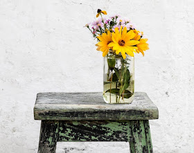 Glass vase of flowers on a stool