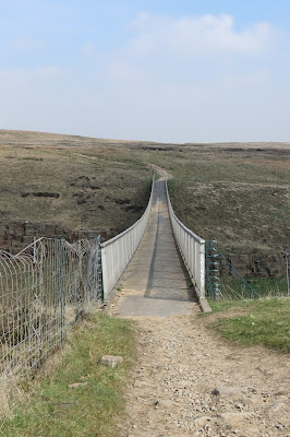 A narrow footbridge stretched out ahead, connecting the moors.