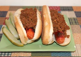 Finished hot dogs on a plate topped with hot dog sauce.