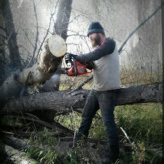 Justin Miller, The Knotty Carver, is using a chainsaw to cut large pieces off of a fallen down tree.